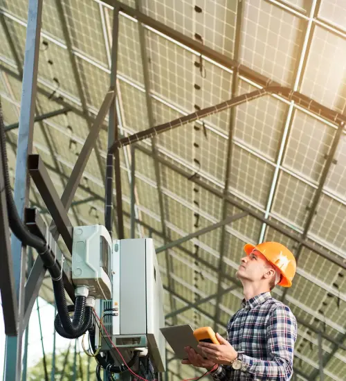 Engineer checking the operation of solar power station. Woker in helmet and with laptop and sensor in his hands, looking up. Science technology. Global warming. Green energy.